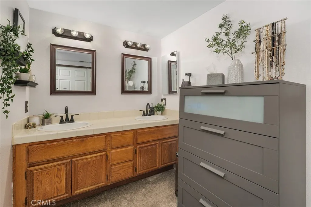 The open en suite bathroom has a dual sink vanity.