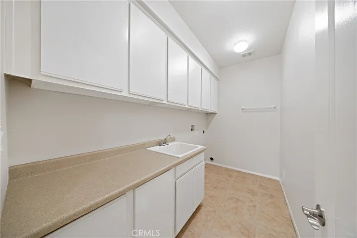 Laundry room with lots of cabinets and a convenient sink.
