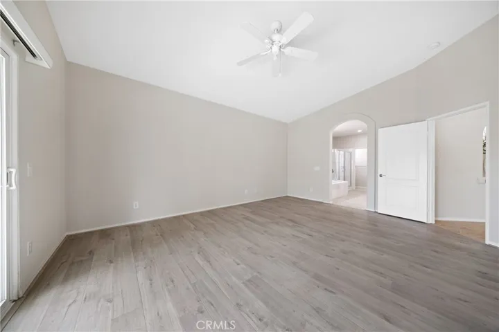 Primary bedroom with vaulted ceiling and overhead fan.