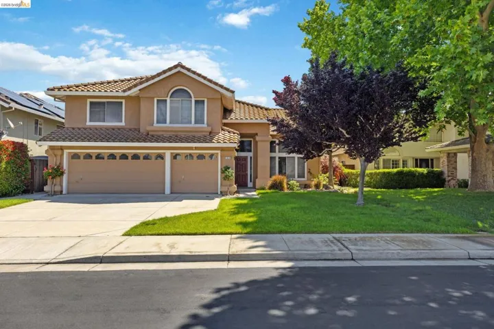 Stucco exterior residence featuring a tile roof, an arched window, and a two-car garage