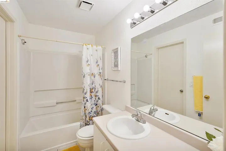 Full bathroom featuring a white integrated bathtub and shower, a white toilet, and a vanity with an integrated sink