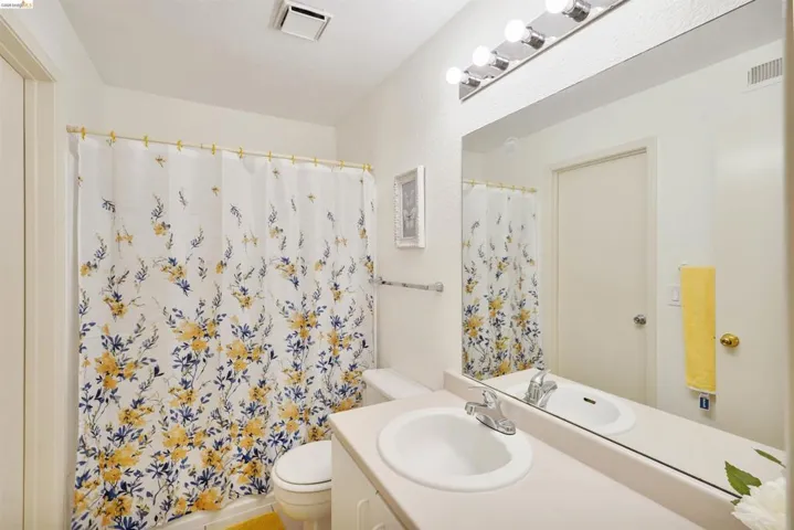Bathroom featuring a single vanity with an integrated sink, polished chrome faucet, and a large wall-mounted mirror