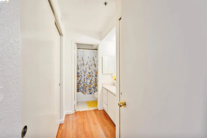 Hallway featuring wood-finish flooring, white walls, and a recessed ceiling light