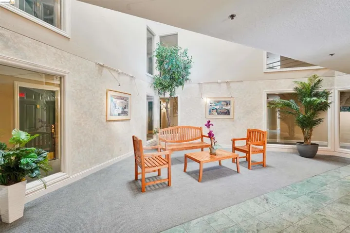 Spacious interior atrium featuring a vaulted ceiling, light-toned textured walls, recessed lighting, and a combination of carpet and tiled flooring