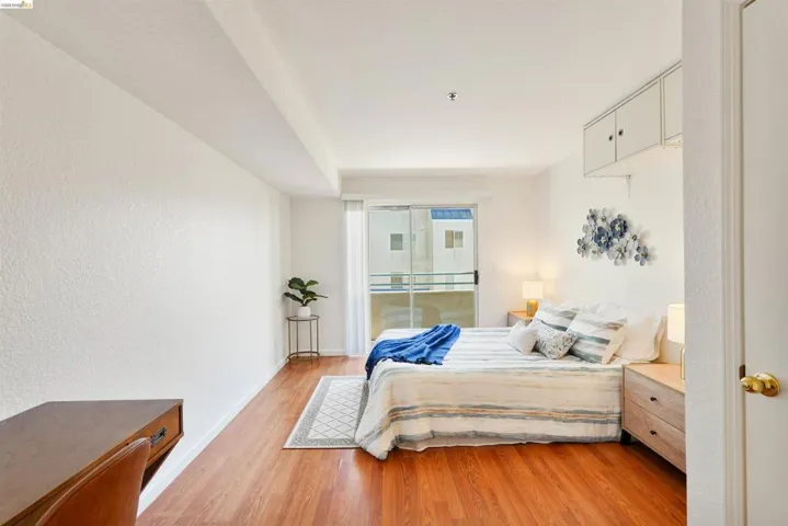 Bright living space featuring wood-finish flooring, white walls, and built-in overhead cabinetry
