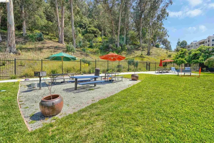 Expansive lawn area with a gravel patio featuring picnic tables and a built-in barbecue grill