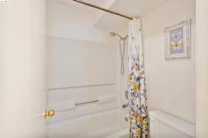 White tub and shower combination with a curved shower rod and an integrated soap dish