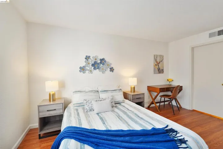 Room featuring wood-finish flooring, white walls, and a recessed air vent