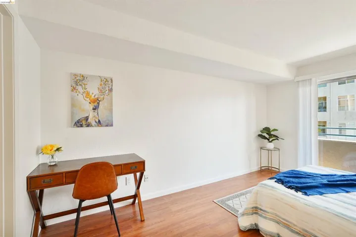Spacious interior featuring wood-finish flooring, white walls, and a large window with white vertical blinds