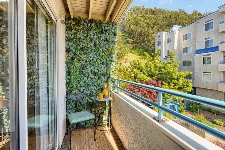 Private balcony featuring a decorative green wall, wood-finish flooring, and a light blue metal railing