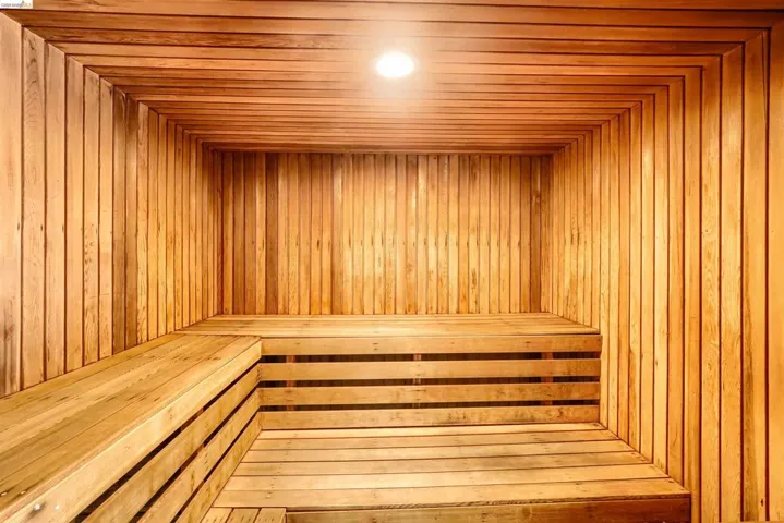 Custom-built sauna featuring light wood paneling, multi-level slatted benches, and recessed ceiling lighting