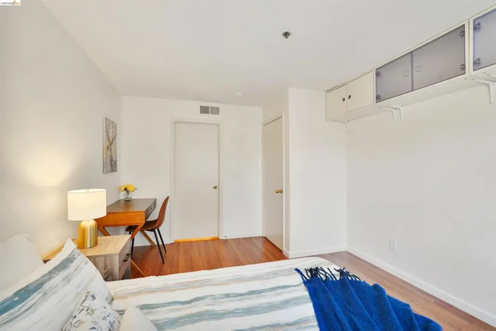Room with wood-finish flooring, white painted walls, and an overhead lighting fixture