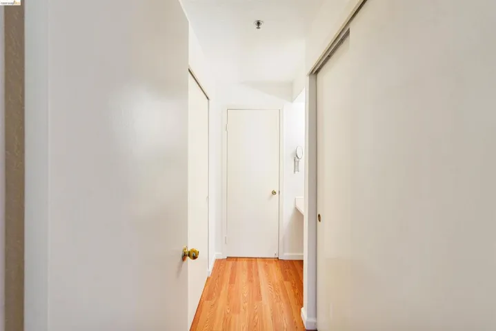 Hallway featuring wood-finish flooring, white walls, and bright overhead lighting