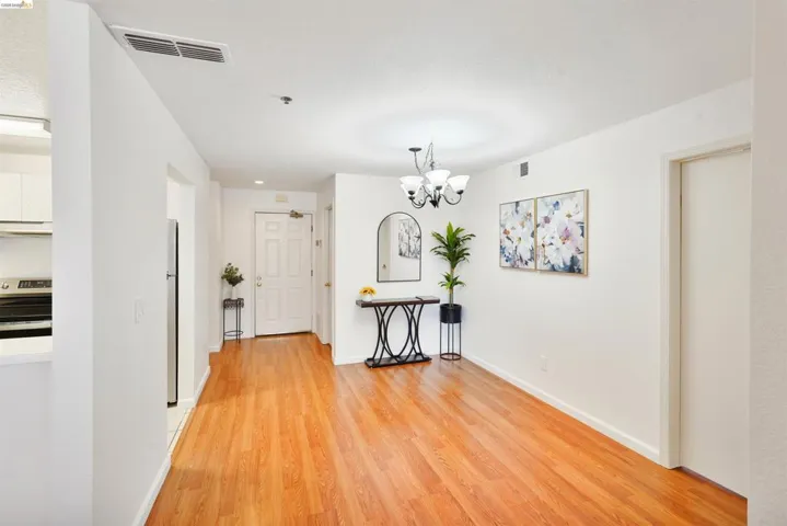 Open concept living area featuring wood-finish flooring, white walls, and a four-light chandelier