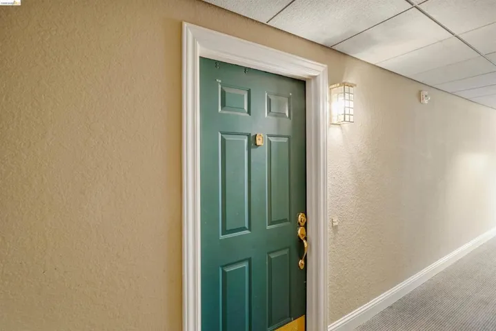 Entryway featuring a paneled door with a brass handle, a rectangular wall sconce, and textured wall finishes