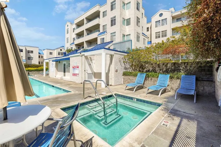 Outdoor aquatic area featuring a rectangular pool and an adjacent square spa with stainless steel railings