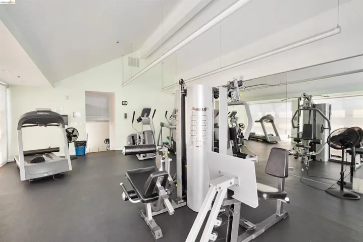 Fitness center featuring a vaulted ceiling and extensive mirrored wall