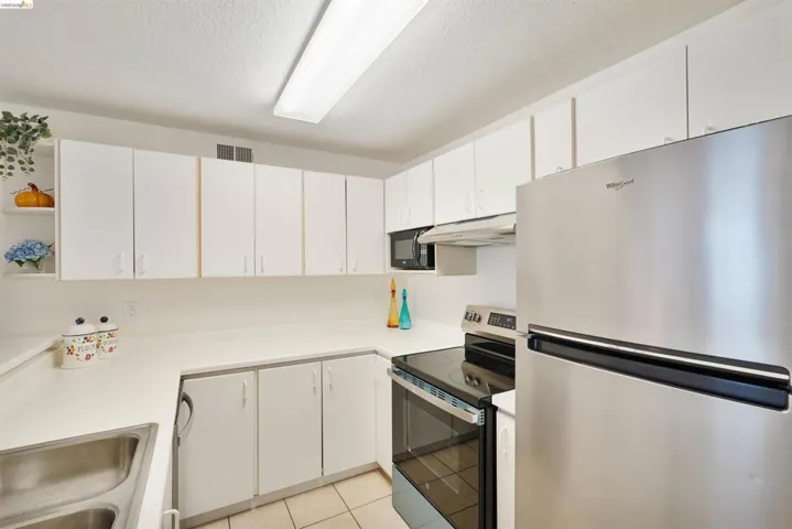 U-shaped kitchen featuring white cabinetry, light-toned countertops, and tile flooring