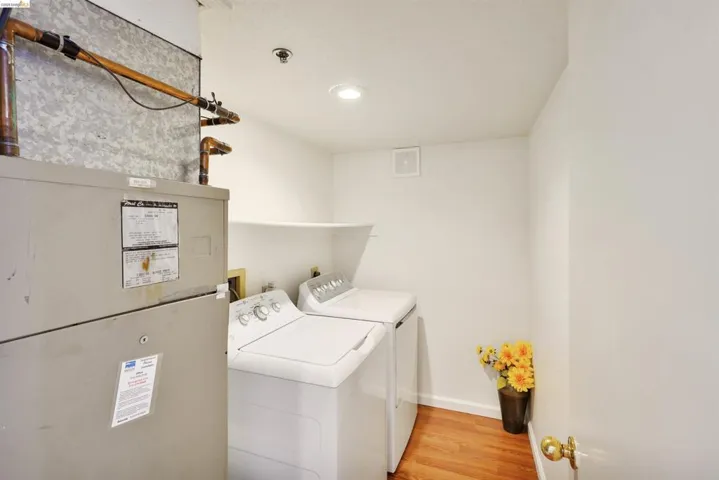 Dedicated utility space featuring a furnace, plumbing, and wood-finish flooring