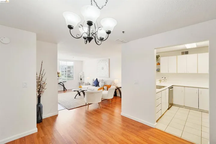 Open concept interior featuring wood-finish flooring, a contemporary chandelier, and a bright white color palette