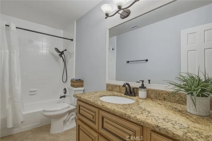 Secondary bathroom with granite countertop vanity and a tub/shower combination