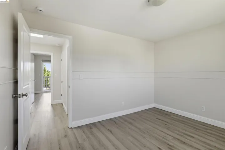 Bright interior space featuring wood-finish flooring, white baseboards, and a two-tone wall treatment with decorative trim