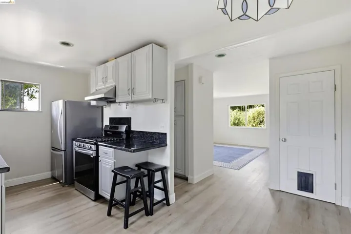 Modern kitchen featuring light wood-finish flooring, white cabinetry, and dark countertops