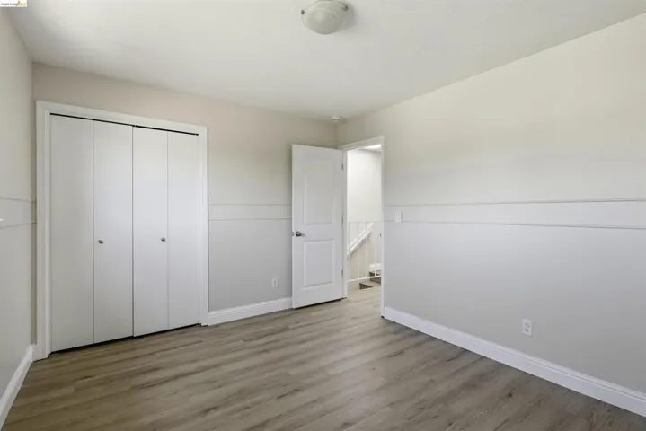 Room featuring wood-finish flooring, two-tone painted walls with wainscoting, and a white bi-fold closet