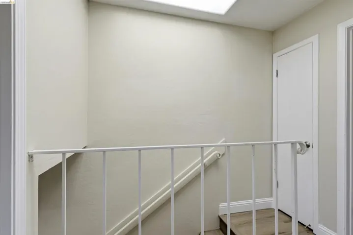 Stairwell with wood-finish flooring, white balustrade, and overhead skylight