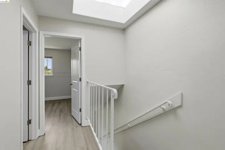 Hallway with wood-finish flooring and a skylight