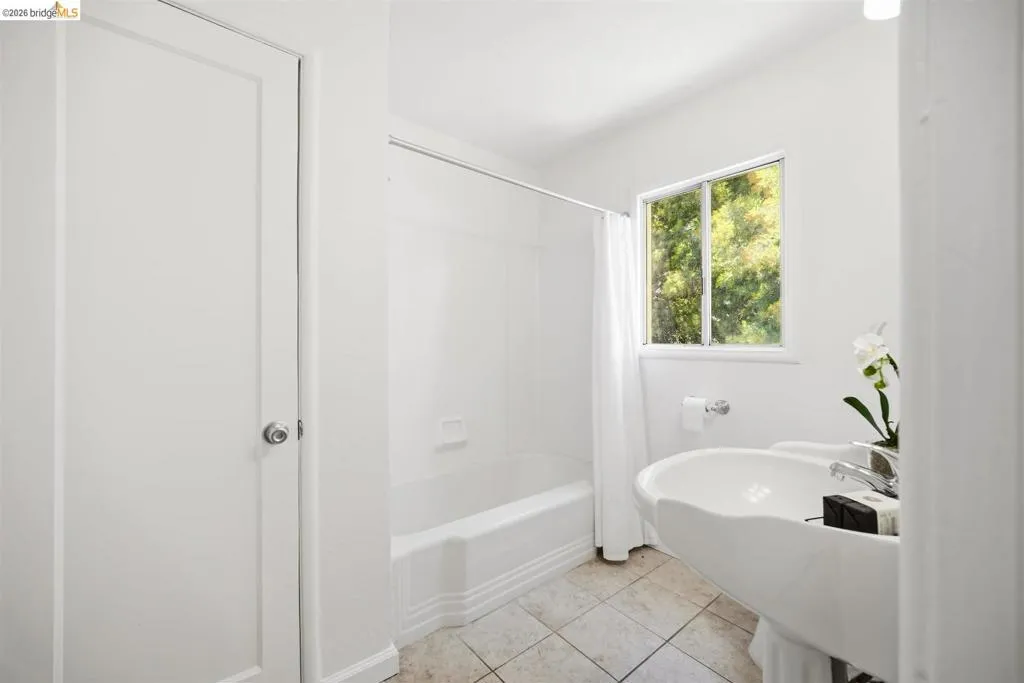 Bathroom featuring a pedestal sink with chrome faucet, a standard tub/shower combination, and tiled flooring
