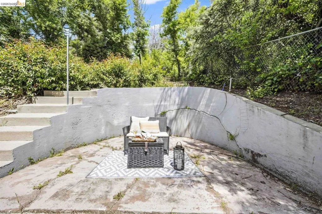 Concrete patio area featuring a terraced retaining wall and built-in concrete steps with a metal handrail