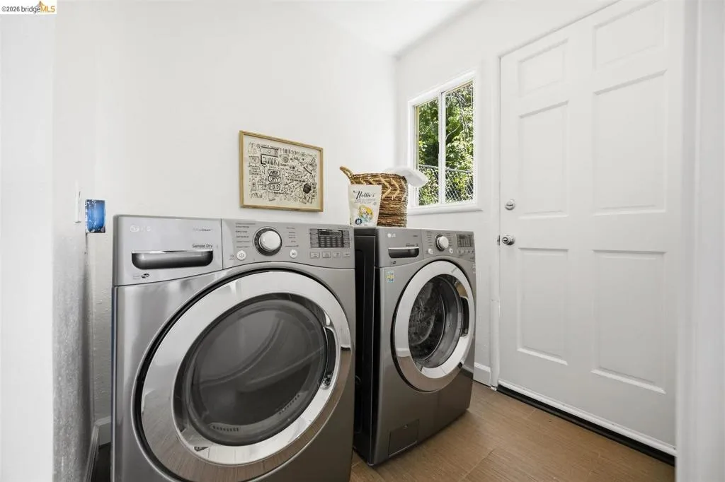 Dedicated utility room featuring light wood-finish flooring, a multi-pane window, and a paneled entry door
