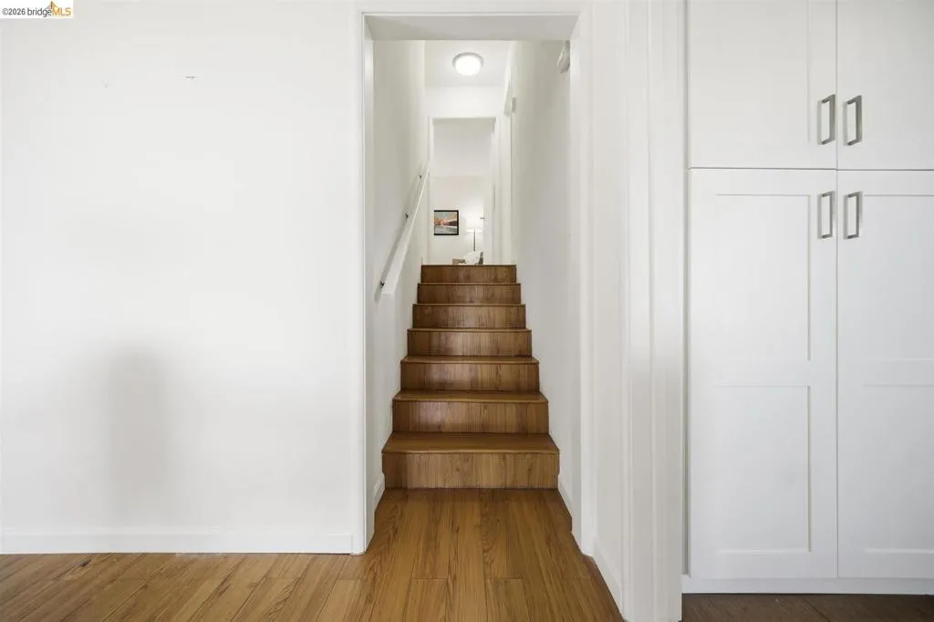Wood-finish flooring extending to natural wood stairs with a white handrail