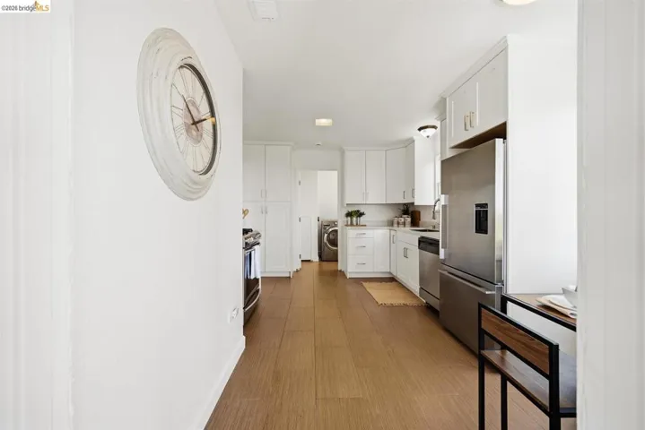 Contemporary kitchen with wood-finish flooring, white cabinetry, stainless steel appliances, and a built-in stainless steel refrigerator