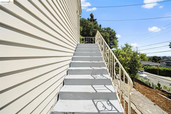 Exterior staircase featuring decorative wrought iron railings, concrete steps, and horizontal siding
