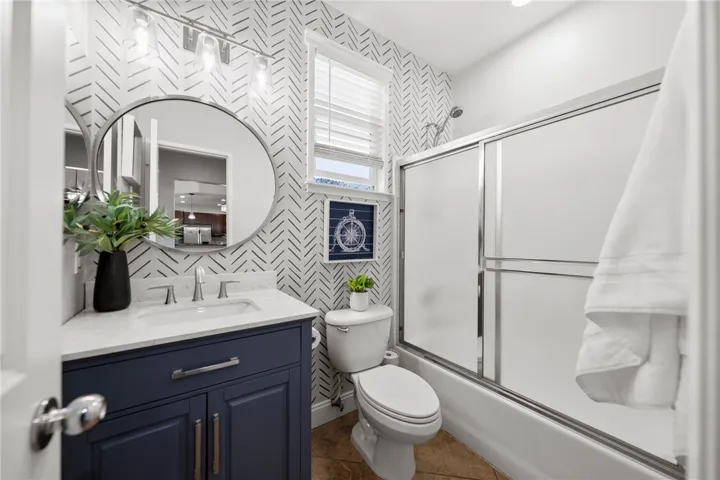 Upgraded Secondary Bathroom with new vanity, mirror, custom light fixtures and oversized tile flooring.