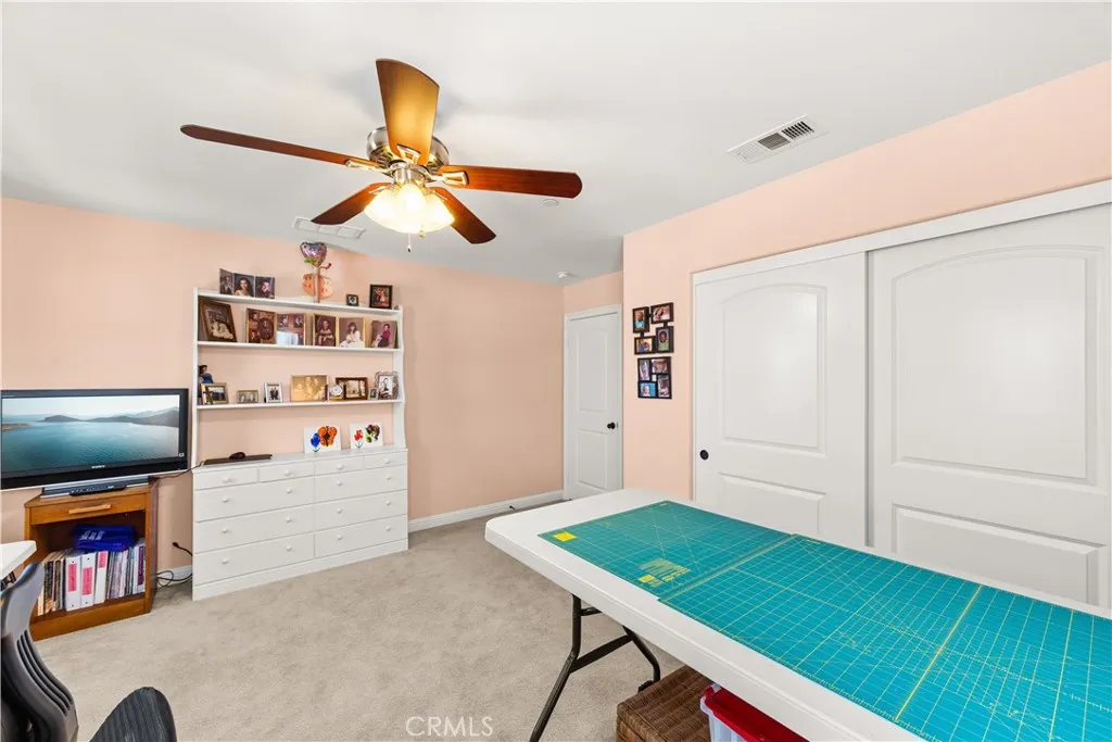Upstairs bed 2 used as a craft room with lighted ceiling fan and plush carpet
