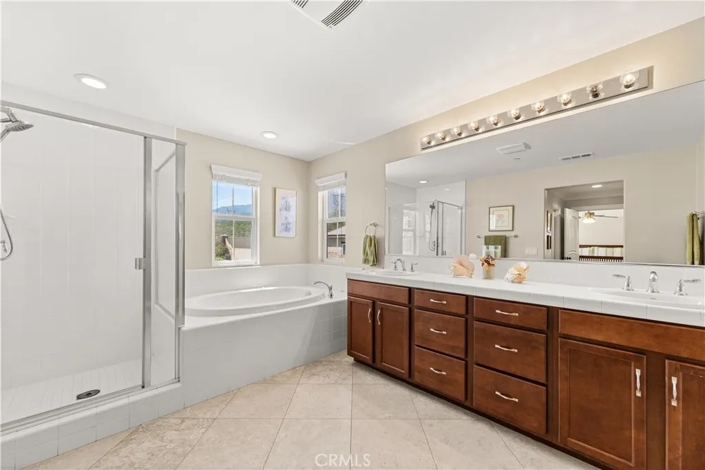 Primary bath with his and her sinks, stand up shower, soaking tub, private commode, and mountain views