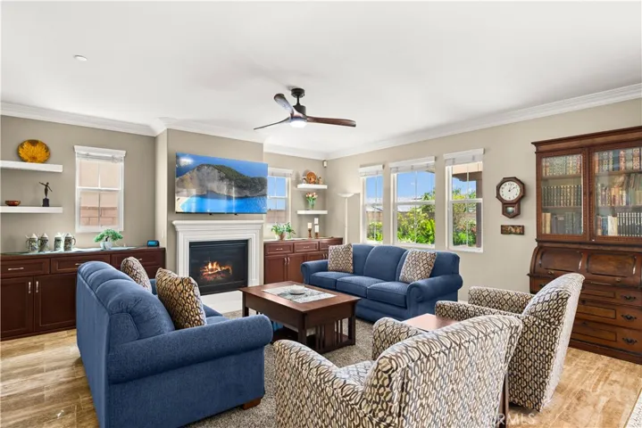 Lighted ceiling fan in family room with custom cabinetry in the alcoves and a gas burning fireplace
