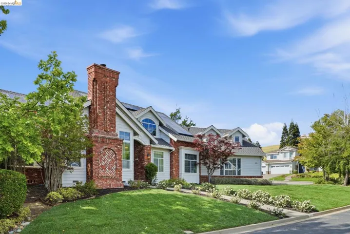 Brick and siding exterior featuring a prominent chimney, arched window, and solar panels