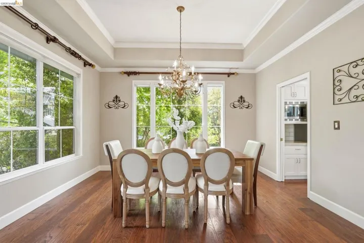 Dining area featuring wood-finish flooring, a tray ceiling, and a chandelier
