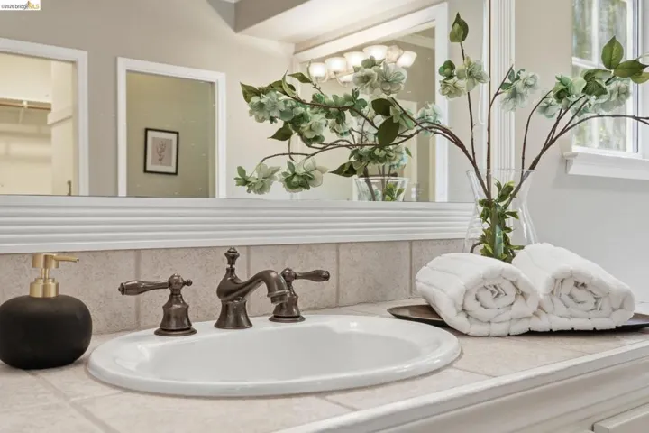 Bathroom vanity featuring a white oval undermount sink, oil-rubbed bronze widespread faucet, and a tiled countertop