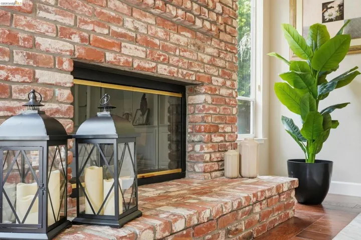 Brick fireplace featuring a raised hearth, a black firebox, and a visible window