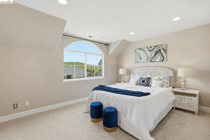 Arched window with multiple panes, recessed ceiling lighting, light-toned carpet flooring, neutral painted walls, and white baseboards