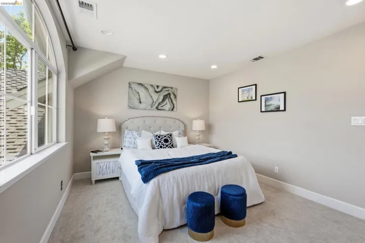 Arched window with gridded panes, recessed ceiling lighting, textured wall-to-wall carpeting, and neutral paint finishes