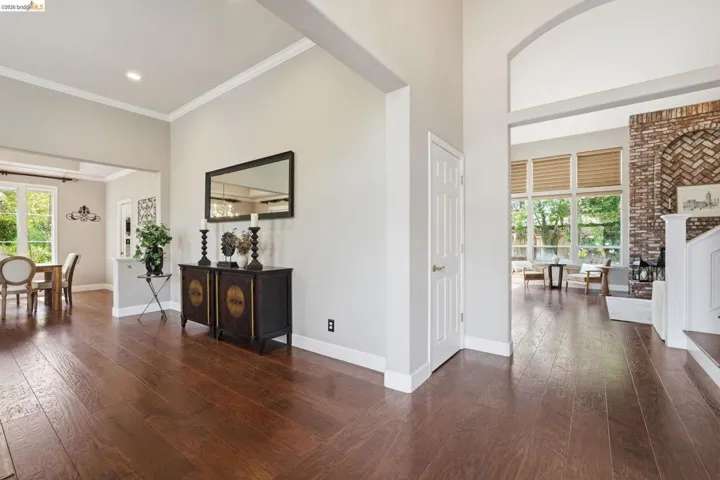 Open-concept interior featuring wood-finish flooring, high ceilings, and a brick fireplace with a white mantel