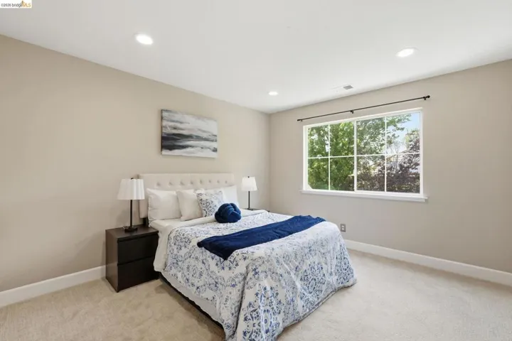 Bedroom featuring light neutral wall paint, recessed lighting, a large window with white framing, white baseboards, and soft carpet flooring