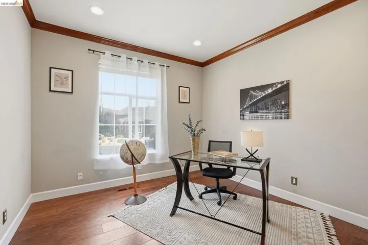 Versatile room featuring wood-finish flooring, white baseboards, and crown molding