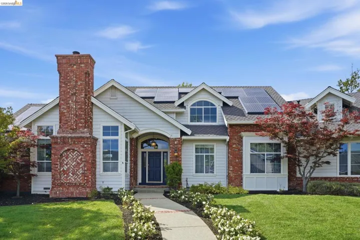 Traditional-style residence featuring a brick and siding facade, a prominent brick chimney, and a landscaped front yard with a curved walkway